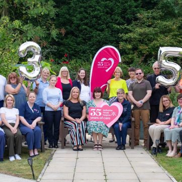 Staff at Katharine House Hospice gathering in the gardens holding balloons and signs celebrating the Hospice's 35th anniversary.