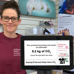 Retail Assistant, Tammy, stands behind the till displaying the CO2 savings of a recent purchase.