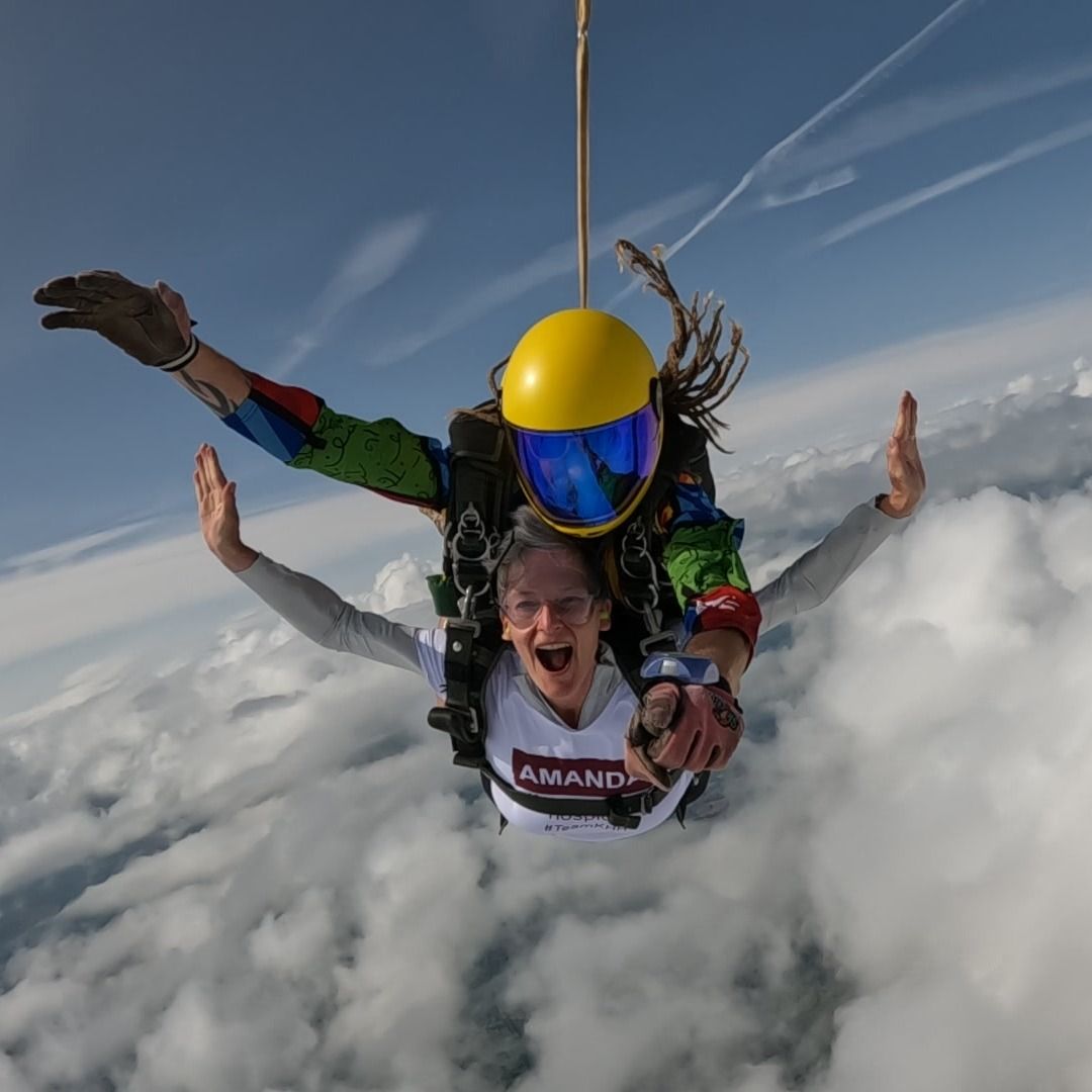 Amanda Brooke and her tandem skydiving instructor smiling mid-jump during a charity skydive fundraiser for Katharine House Hospice.