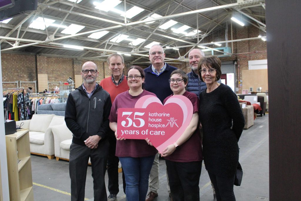 four members of staff who worked on the expansion project standing in the shop holding a 35 years of care logo