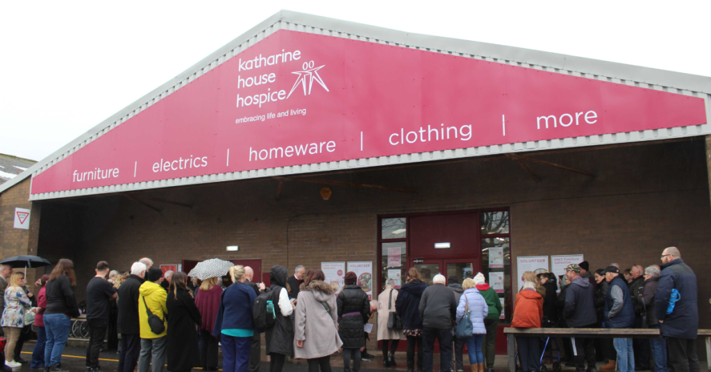 Hundreds of people in coats queuing outside the shop entrance